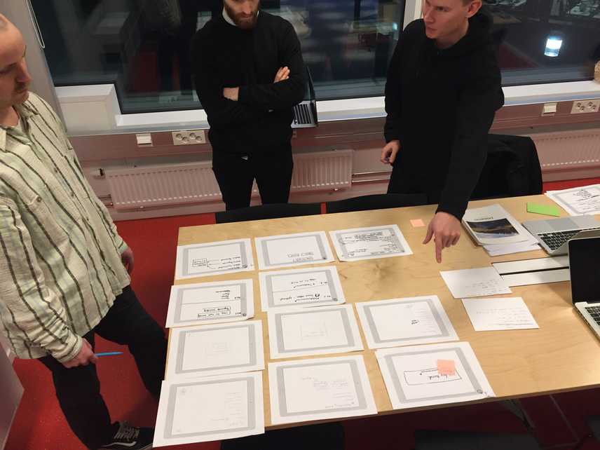 The team working on the product discussing the different sketches made by the staff